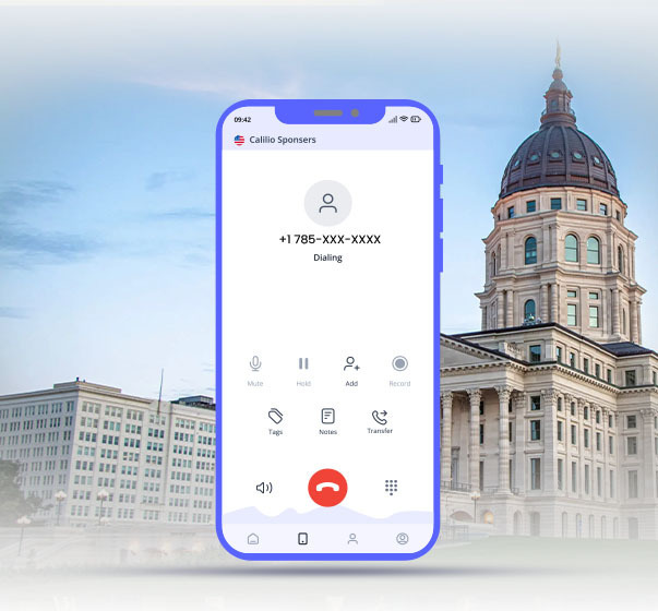 Cell phone dialing 785 area code number with Kansas State Capitol in background